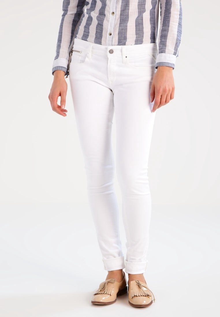 Vita smala jeans med en slät yta, traditionell femfickdesign och en enkel knappstängning. I kombination med bruna loafers med fransar.