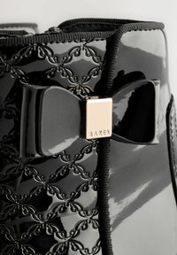 Schwarze Lackleder-Stiefelette mit geprägtem Blumenmuster, dekorativem Bogen und goldenen Hardware-Akzenten mit dem "BAKER"-Logo.