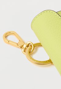 Πράσινο δερμάτινο μπρελόκ με χρυσό μεταλλικό κρίκο καραμπίνα και δαχτυλίδι. Διαθέτει ανάγλυφο λογότυπο στο δαχτυλίδι και ομαλή υφή.