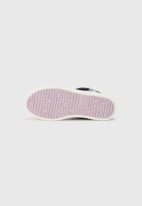 Sneaker sole featuring a textured, rubber surface with circular patterns, predominantly lavender in color with a white edge.