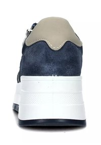 Marinblå mockaskor med en beigefärgad läderklack, vit texturerad sula och släta detaljer, med en zigzag-sömnadsdetalj.