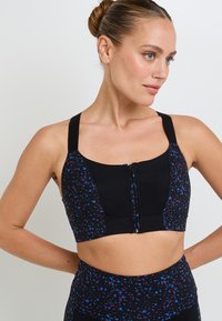 Reggiseno sportivo con corpo nero, dotato di una zip frontale e una parte inferiore a fantasia nera con accenti turchesi e viola. Spalline larghe.
