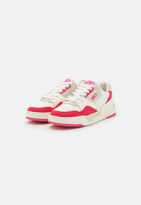 White and pink sneakers featuring a textured upper, padded collar, and durable rubber sole with brand lettering on the tongue.