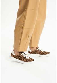 Tenisky s leopardím potiskem a bílými tkaničkami. Měkký materiál, zaoblená špička, texturovaný design. V kombinaci s béžovými, lehkými, zkrácenými kalhotami.