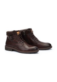 Botas de cuero marrón hasta el tobillo con punta redonda, diseño de cordones y cremallera lateral. Presentan un acento beige en el cuello y una superficie texturizada.