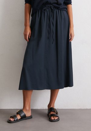 Gonna midi blu navy con vita elastica e cordoncino, dalla texture liscia, abbinata a sandali neri con tacco a blocco e fibbia dorata.