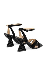 Sandalias de tacón alto negras con tiras de ante, hebilla en el tobillo y tacones con cono texturizado adornados con tachuelas redondas.
