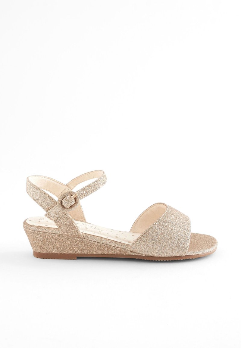 Glitterige gouden wedge sandaal met een open teen, een enkelbandje en een textuur in de binnenzool. Platte zool en een gladde afwerking.