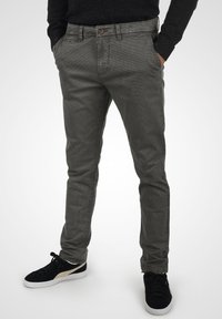 Szare spodnie z bawełny chambray o slim fit, z przednimi kieszeniami, zapięciem na guzik oraz subtelnym wzorem teksturowanym. W połączeniu z czarnymi sneakersami.