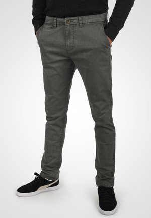 Pantalons en chambray de coton gris avec une coupe slim, comportant des poches avant, une fermeture à bouton et un motif texturé subtil. Associés à des baskets noires.