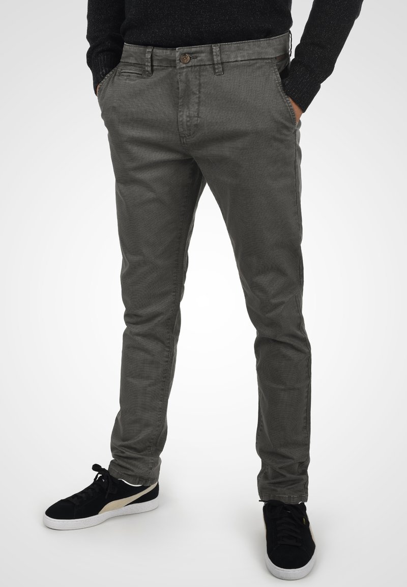 Szare spodnie z bawełny chambray o slim fit, z przednimi kieszeniami, zapięciem na guzik oraz subtelnym wzorem teksturowanym. W połączeniu z czarnymi sneakersami.