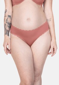 Ribbed, rose-colored underwear with scalloped lace trim on the waistband. Soft texture, mid-rise cut, featuring a smooth finish.