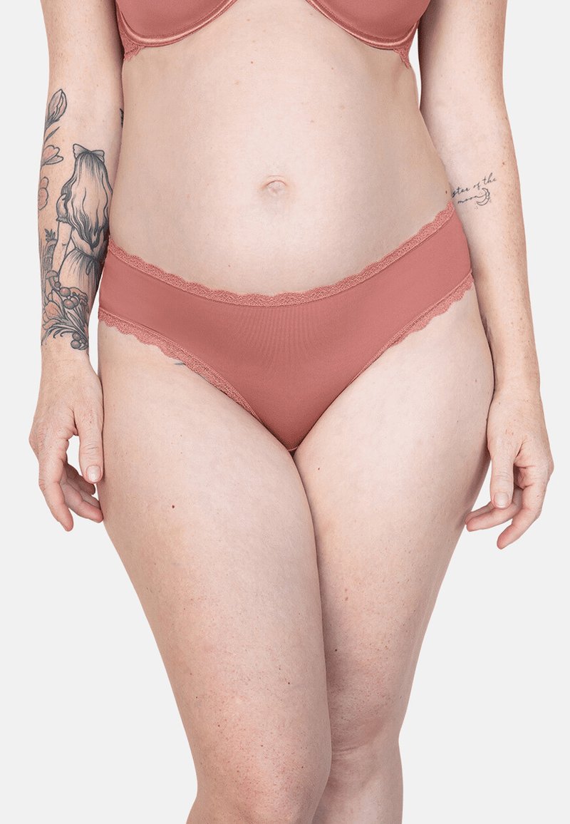 Ribbed, rose-colored underwear with scalloped lace trim on the waistband. Soft texture, mid-rise cut, featuring a smooth finish.