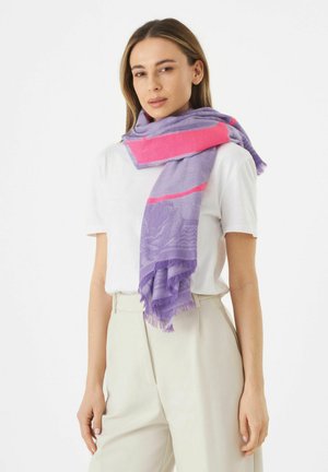 Leichte lila Schal mit pinken Akzenten, mit einem strukturierten Muster und fransigen Kanten, getragen über einem weißen Hemd.