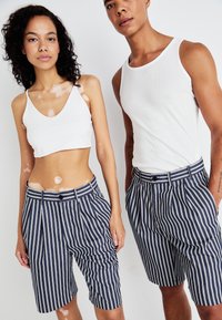 Stripete marineblå shorts med skreddersydd passform, med knappeåpning og lommer, brukt sammen med en enkel hvit tanktop.