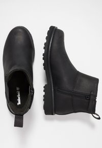 Black leather ankle boots with a side zipper, textured surface, rubber sole, and pull tab, featuring a rugged design and minimalistic style.