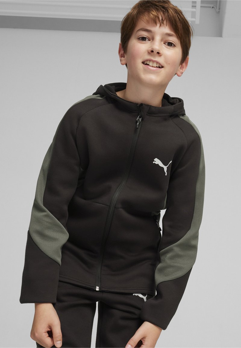Sudadera negra con detalles en verde oscuro, con cierre de cremallera y un logo de Puma blanco en el pecho. Tela suave y texturizada con un diseño deportivo.