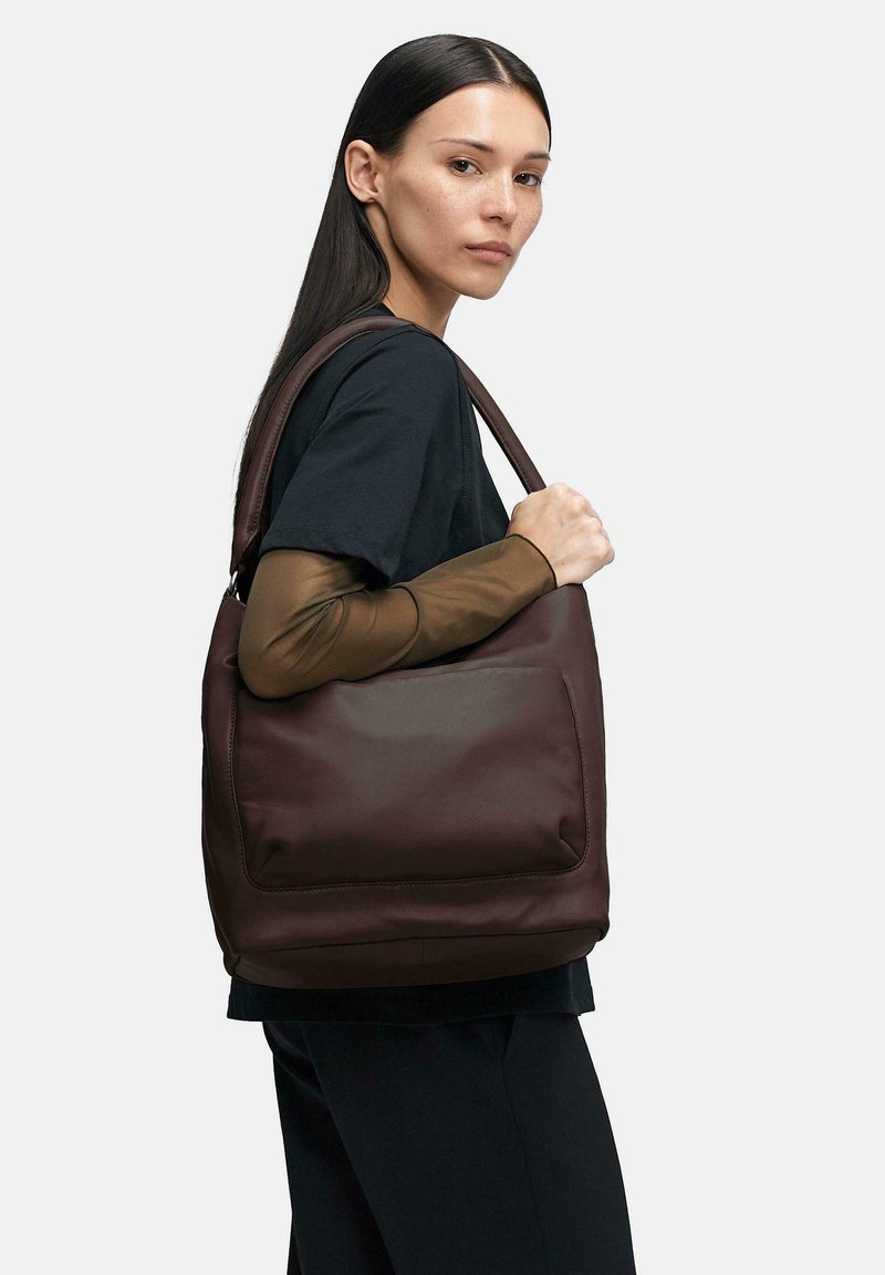 Brązowa skórzana torba na ramię o gładkim wykończeniu i przedniej kieszeni, charakteryzująca się usztywnionym kształtem oraz szerokim, wygodnym paskiem.