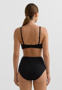 Čierny dvojdielny plavky s nastaviteľnou podprsenkou a vysokým pásom na spodku. Jemná textúra s minimalistickým dizajnom bez viditeľných vzorov.