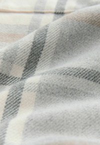 Tela de cuadro gris y crema con una superficie suave y texturizada. El patrón presenta líneas entrelazadas y diferentes tonalidades de gris.