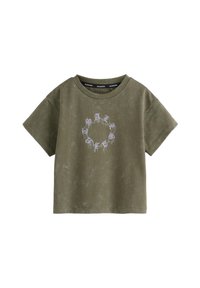 Olivgrön bomulls-t-shirt med korta ärmar, med en cirkulär design i ljuslila på framsidan. Mjuk textur, avslappnad passform.