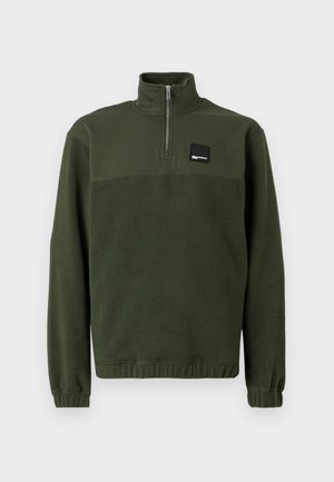 Tmavozelený fleece pulóver s štvrťzipom, vysokým golierom, elastickými manžetami a lemom, a malou obdĺžnikovou čiernou nášivkou na hrudi.