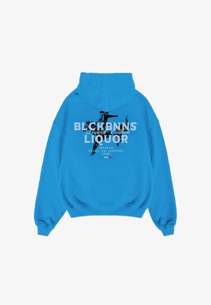 Blauwe sweatshirt met capuchon. Heeft een groot grafisch tekstontwerp op de achterkant in zwart-wit, met details van sterke drankmerken.