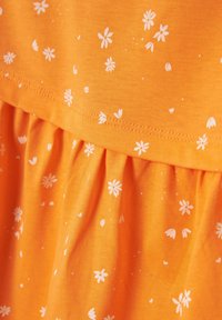 Vestido naranja con un patrón floral blanco, que presenta pliegues texturizados en el dobladillo y una sección superior lisa. El material parece suave y ligero.