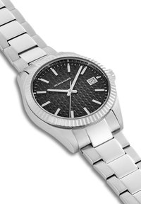 Montre en acier inoxydable argenté avec un cadran noir texturé, des index horaires argentés et une fenêtre de date. Elle dispose d'une lunette polie et d'un bracelet à maillons.