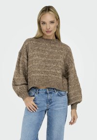 Pull en maille texturé marron avec un col montant et des manches ballons, associé à un jean droit bleu clair, au design minimaliste.