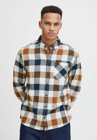 Camicia a maniche lunghe in flanella da uomo in plaid bianco, blu navy e marrone. Presenta un colletto button-down e una tasca sul petto. Texture morbida.