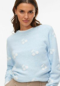 Jasnoniebieski sweter z miękkiego materiału ozdobiony białymi motywami wiśni. Okrągły dekolt, długie rękawy i wygodne dopasowanie.