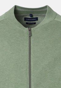 Ljusgrön dragkedjesweater med ribbad krage, metalldragkedja och varumärkesetikett "Casa Moda" inuti kragen.