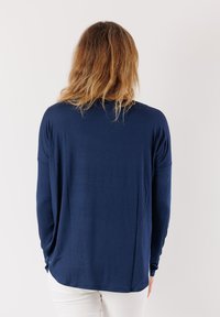 Maglietta a maniche lunghe blu navy con vestibilità rilassata e scollo rotondo, realizzata in tessuto morbido, con spalle scese e orlo curvato.