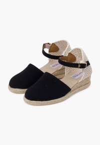 Zwarte canvas espadrilles met een sleehak, voorzien van een geweven enkelband en een beige jute zool. Soepele textuur met minimale details.