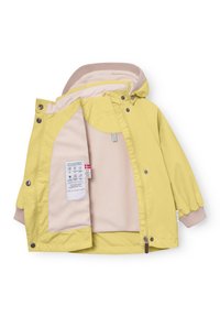 Rumena otroška jakna s kapuco, obložena z bež flisom, s pritisnimi gumbi in notranjo etiketo, ki prikazuje podatke o tkanini in nezi.