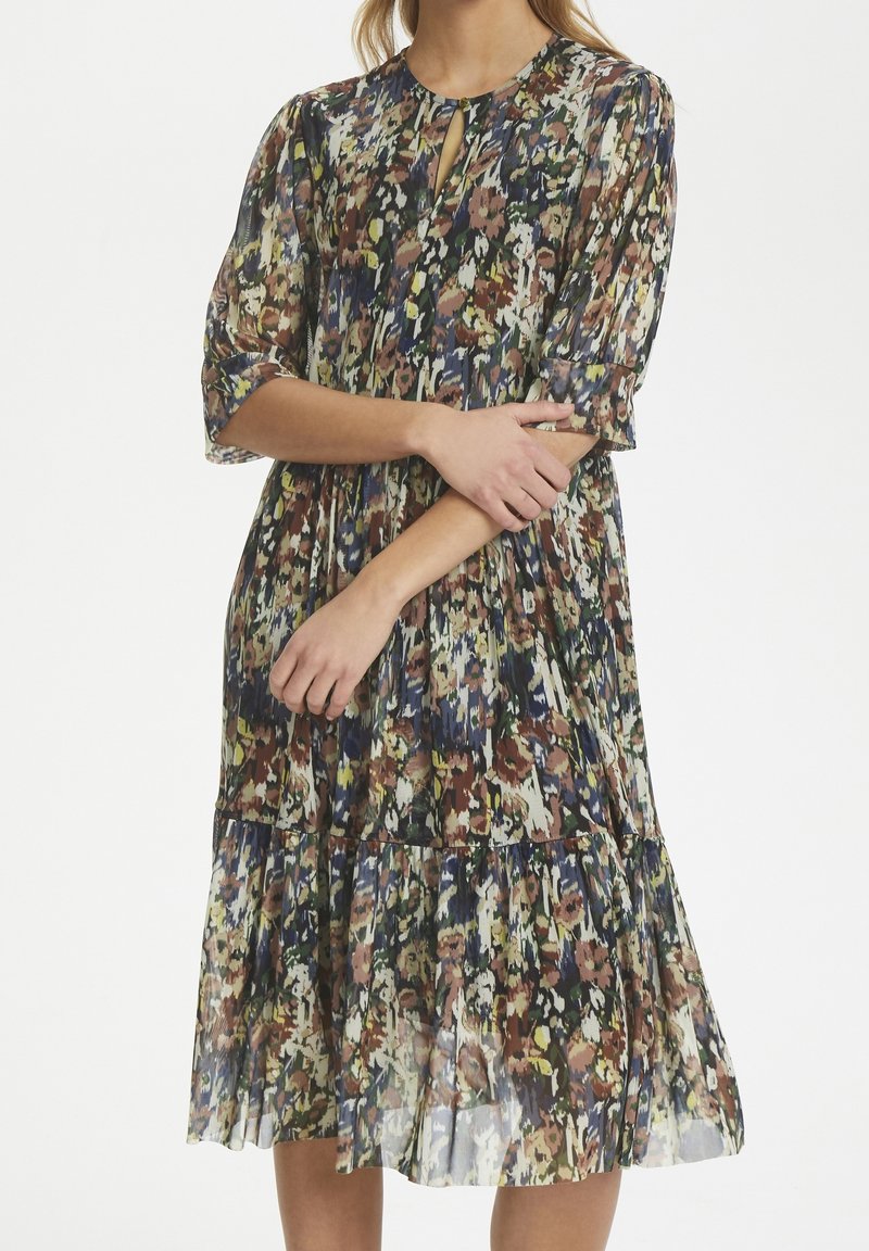 Robe midi florale en tissu transparent, avec un col rond, un détail en trou de serrure et un ourlet volanté. Les couleurs incluent le vert, le marron et le bleu.