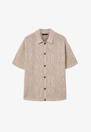 Beige gebreide cardigan met korte mouwen en zwarte knopen, met een patroon van harten en vredestekens in een rasterontwerp.