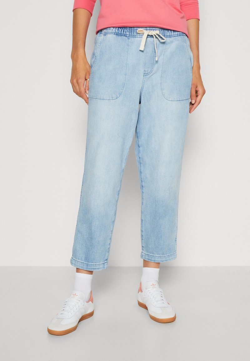 Ljusblå denim joggerbyxor med elastisk midja, dragsko, två framfickor och avskuren nederkant. Matchas med vita sneakers.