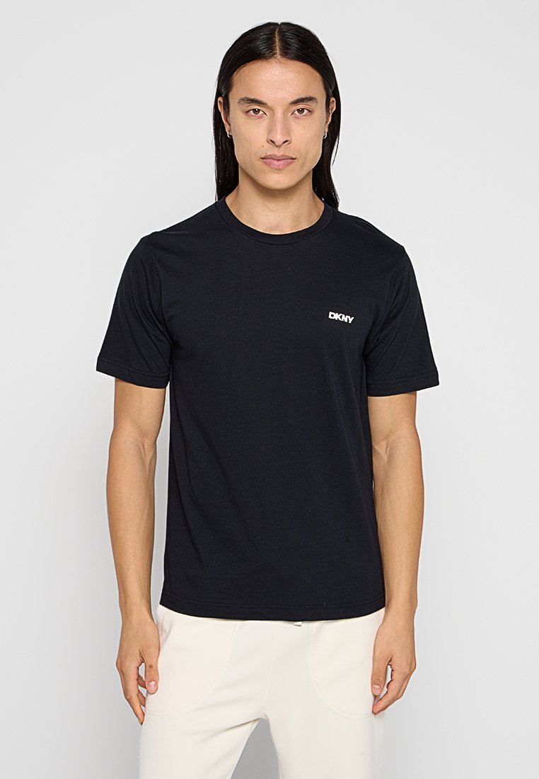 Camiseta negra de manga corta hecha de algodón con cuello redondo y un pequeño logo blanco de DKNY en la parte izquierda del pecho.