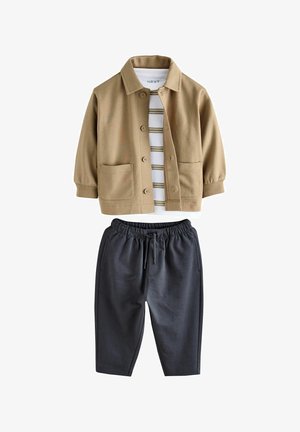 Tan button-up jacket with two front pockets over a white and striped shirt, paired with dark gray elastic waistband pants.