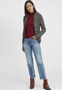 Stickad grå kofta med ribbad bordeauxfärgad polokrage, tillsammans med ljusblå jeans och bruna ankelboots. Har träknappar som detalj.