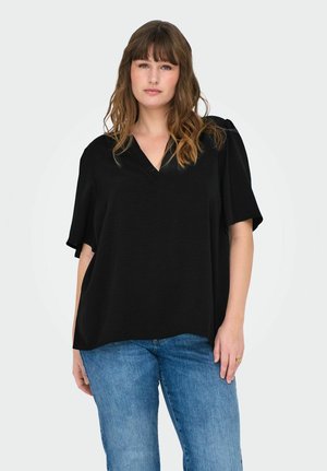 Top negro de cuello en V con mangas cortas, confeccionado en tela ligera. Corte relajado con superficie texturizada, combinado con jeans de mezclilla azul.