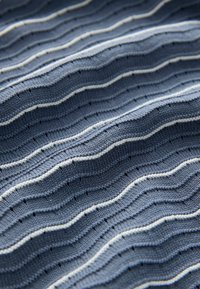 Fala dzianiny z naprzemiennymi ciemnoniebieskimi i jasnoniebieskimi poziomymi paskami oraz cienkimi białymi liniami, ukazująca teksturowane i wypukłe wzory.