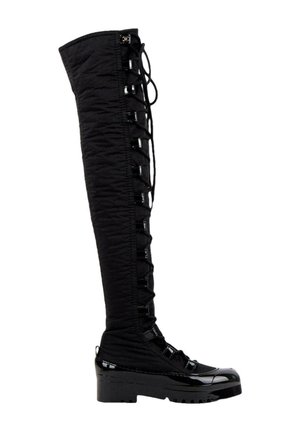 Botte noire au-dessus du genou avec devant à lacets, semelle épaisse et accents brillants sur les orteils et le talon.