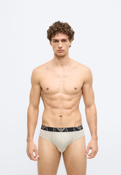 Bézs pamut alsónadrág fekete derékpánttal, amin logó található. A szabás testhez simuló és sima tapintású.