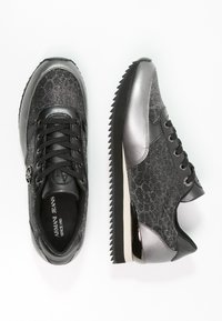 Svarta och silver sneakers med en texturerad ovandel, snörning, metalliska detaljer och en kontrasterande räfflad sula.