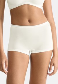 Lysebeige bomulds hipstershorts med glat tekstur, talje i midjestørrelse og sømløst design. Har et diskret brandlogo på taljebåndet.