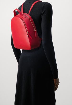 Red leather backpack with a rounded shape, dual zippers, and gold-tone hardware. Textured surface and adjustable shoulder straps.