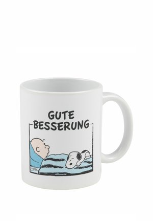 White mug with cartoon of a person and dog lying in bed under blue striped blanket with German text "Gute Besserung" meaning "Get well soon."